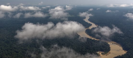 Fotografia aérea com nuvens e rio sinuoso passando pela floresta tropical