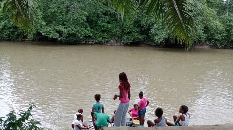 Grupo de mulheres às margens de um rio turvo na floresta tropical