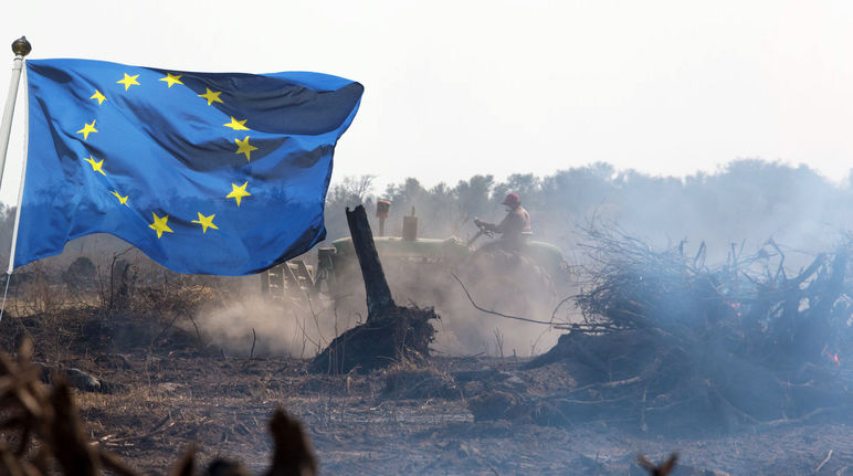 Fotomontagem: A bandeira da UE explode na frente de um trator que remove a vegetação