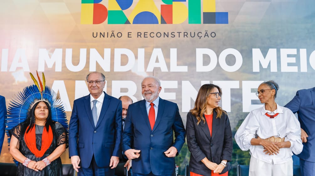 O Presidente Lula e o Vice Alckmin, junto com ministras e ministros, diante de um cartaz sobre o Dia Mundial do Meio-Ambiente