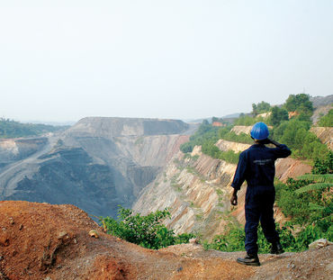 Um trabalhador em frente a uma mina a céu aberto