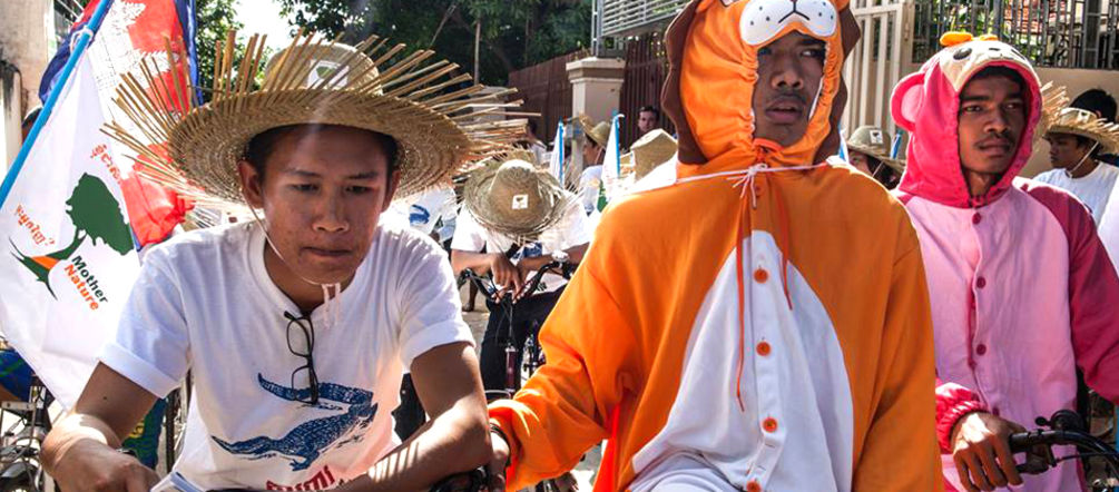 Manifestantes em fantasias de animais em bicicletas no Camboja